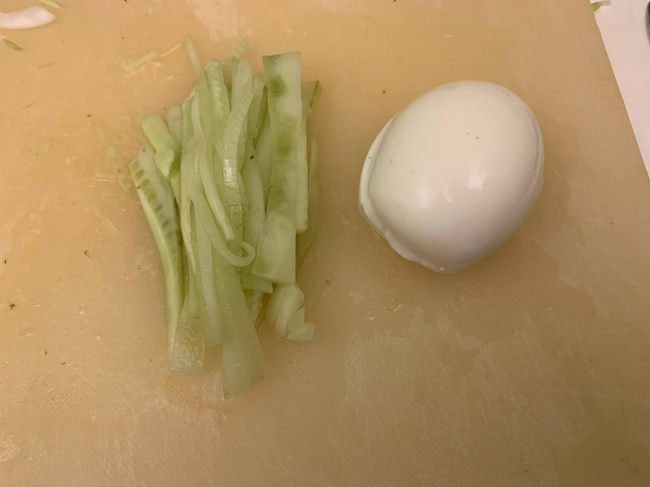 While noodles boil, fry 2 slices of <b>pork</b> from freezer until browned, peel <b>soft boiled egg</b> and cut <b>cucumber</b> into strips.