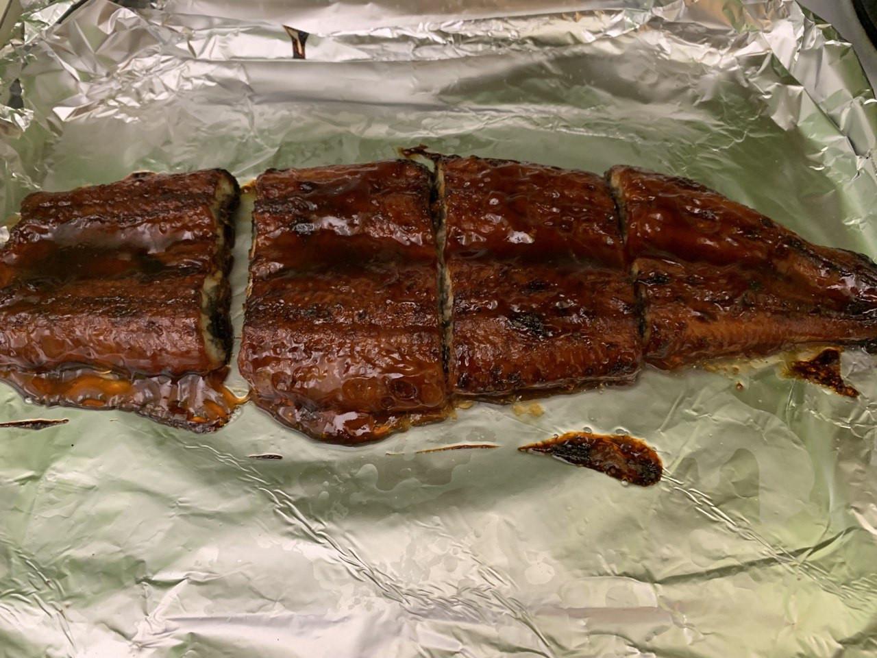 Cut open the unagi pack. Set up a baking tray with foil and spread 1 tsp of oil. Slice unagi into four pieces, arrange on tray, and broil for 7 minutes.