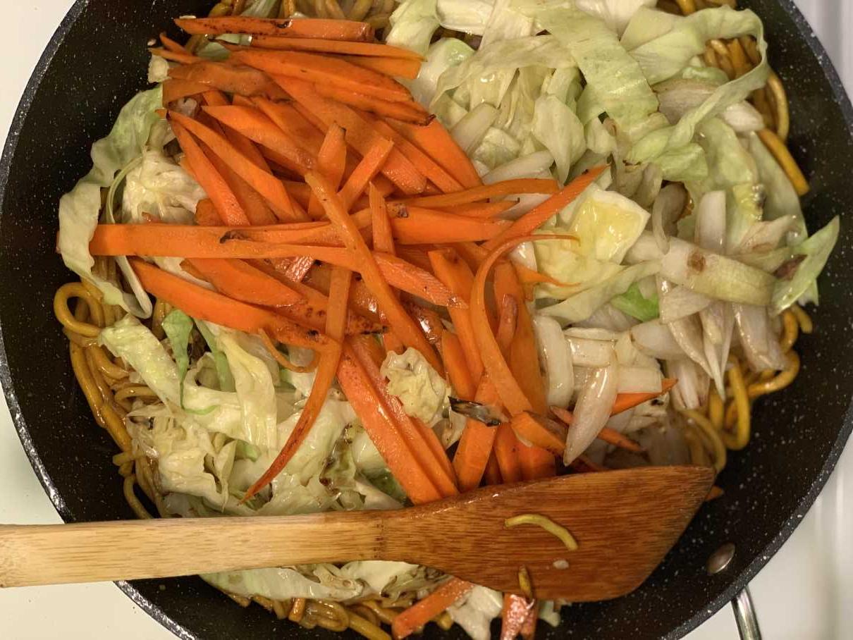 Mix in the <b>yakisoba sauce</b>, <b>teppanyaki butter</b> and then add <b>cooked carrots</b>, <b>cabbage</b>, <b>green onions</b>, and <b>meat</b>. (If doesn't fit, you can serve your veges as a topping instead)